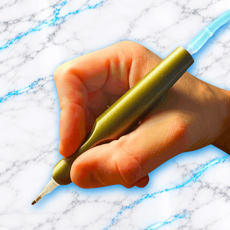 Vue rapprochée du crayon 3D ErgoPro doré métallisé pour Diamond Painting tenu en main, montrant sa poignée ergonomique et son embout pour broderie diamant.