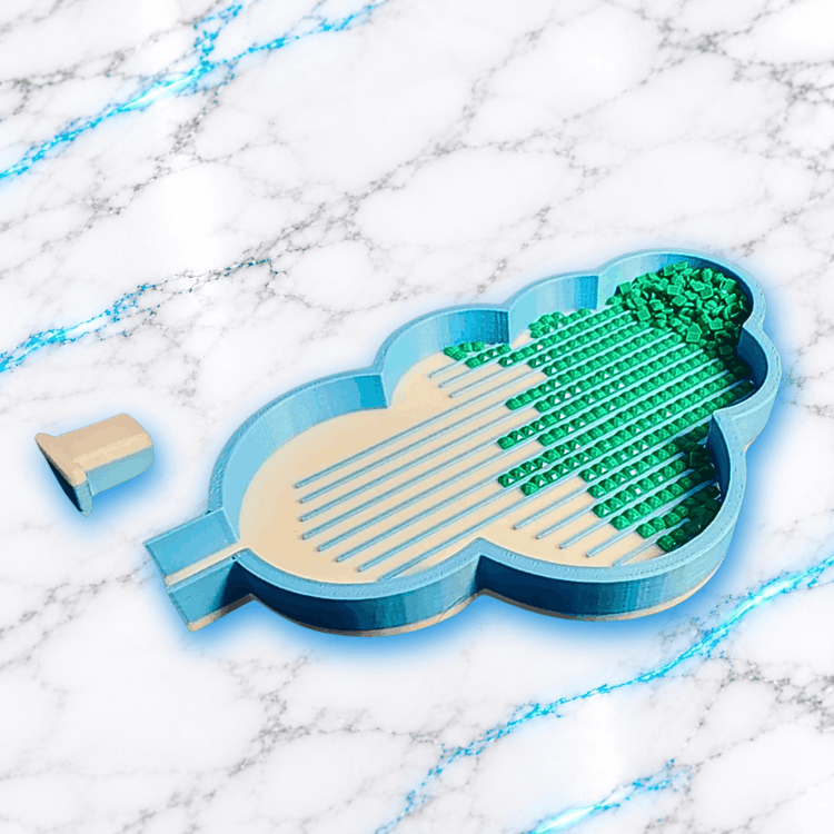 Plateau 3D Diamond Painting Le Nuage UnBrunBarbu, vue de trois quarts montrant ses rebords bleus, son fond beige, ses rainures de tri et ses diamants carrés verts alignés, avec bouchon amovible posé à côté, sur marbre blanc veiné de bleu.