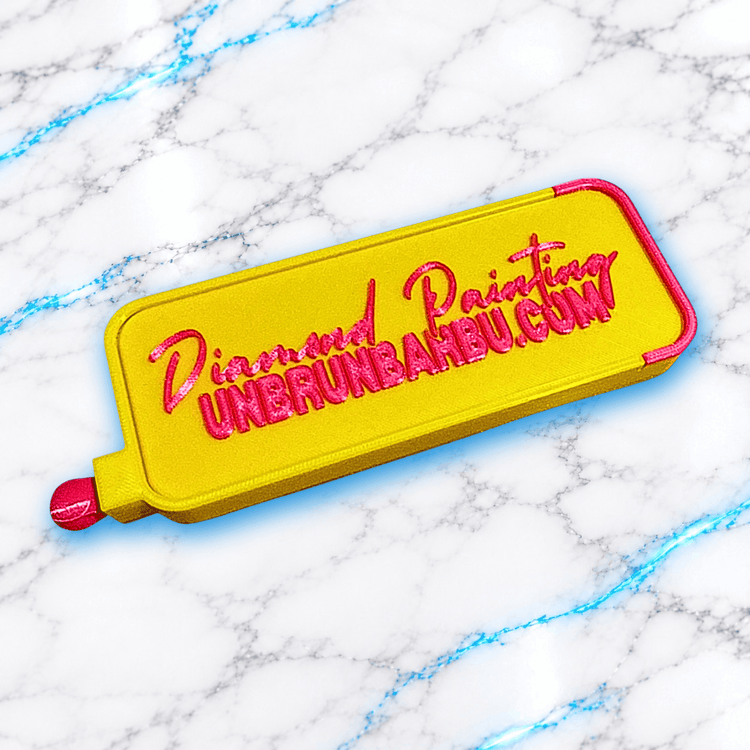 Couvercle jaune et rose fuchsia du plateau 3D Diamond Painting No Washi Wavy XL, avec inscription Diamond Painting UnBrunBarbu.com en relief et languette de fermeture coulissante.