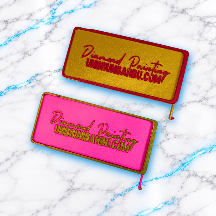 Deux plateaux 3D Diamond Painting WashiLinePro Max UnBrunBarbu, modèles rectangulaires avec inscription en relief, l'un doré et rouge, l'autre rose et doré, avec languettes intégrées.