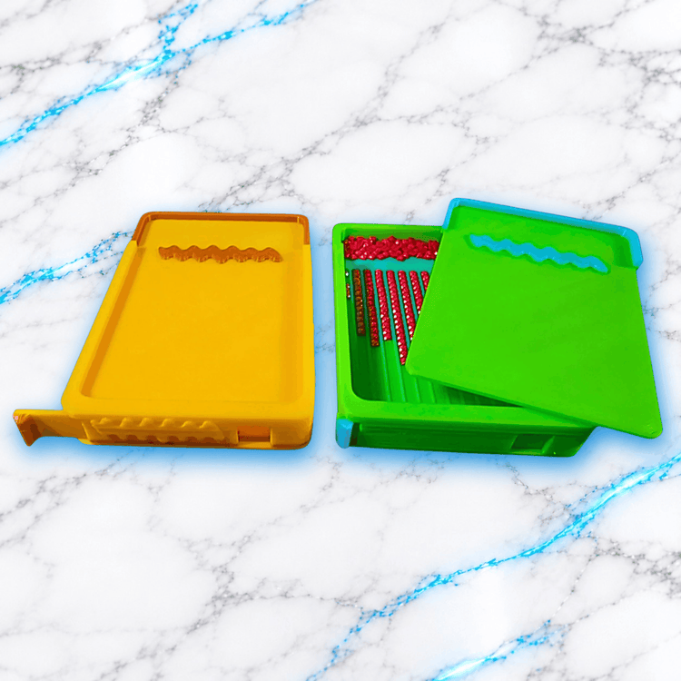 Deux plateaux 3D Diamond Painting WashiLinePro jaune et vert, avec couvercle coulissant partiellement ouvert sur le modele vert, montrant les diamants rouges alignes dans les rainures, fabrication UnBrunBarbu.