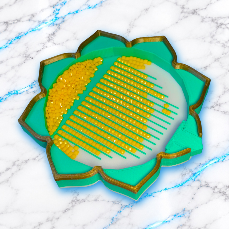 Plateau Diamond Painting Flower Lotus vert menthe à bordure dorée et fond blanc, avec diamants carrés jaunes alignés et bouchon en place.
