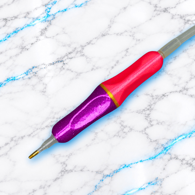 Crayon ergonomique Diamond Painting ErgoDuo Compact rose et violet à bague dorée, avec pointe fine dorée et connexion à un tuyau d’air transparent.