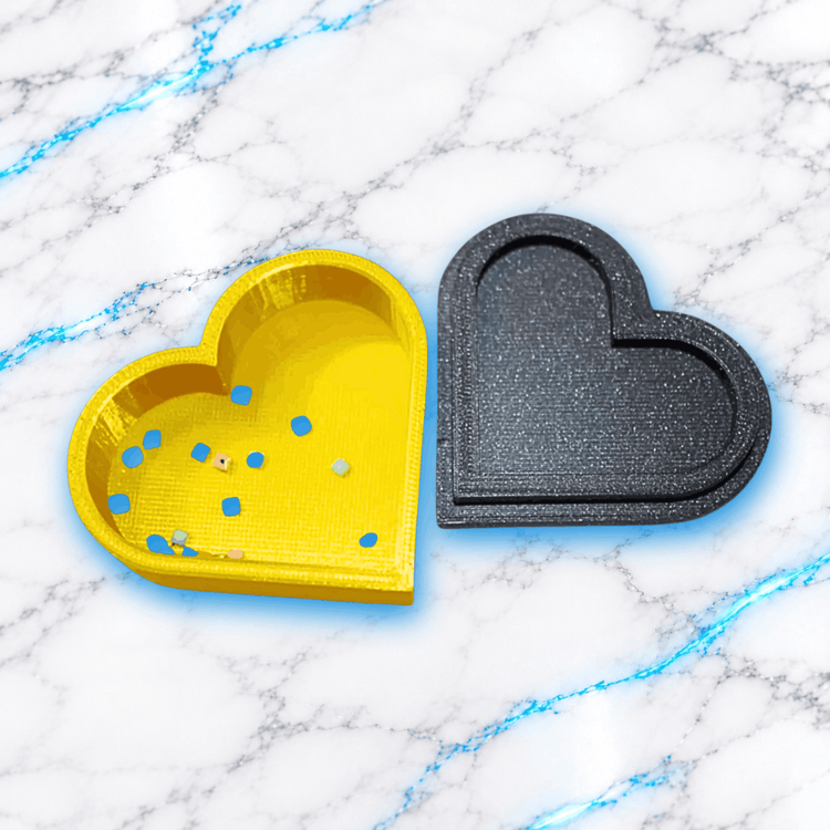 La Love Poubelle UnBrunBarbu ouverte, accessoire Diamond Painting imprimé en 3D en forme de cœur, avec récipient jaune doré contenant des diamants inutilisables et couvercle noir pailleté amovible.