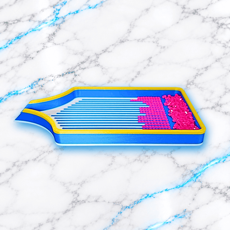 Vue latérale du plateau 3D Diamond Painting Le Big Indispensable 2.0 XXL UnBrunBarbu, bleu avec bordures jaunes, fond blanc à rainures bleues, diamants carrés roses et bec verseur sur la gauche.