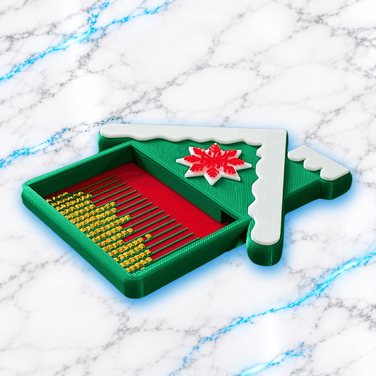 Plateau 3D Diamond Painting Chalet Enneigé UnBrunBarbu vu en perspective, avec compartiment vert, fond rouge à rainures, diamants carrés dorés et décoration de toit enneigé blanc ornée d'un flocon rouge.