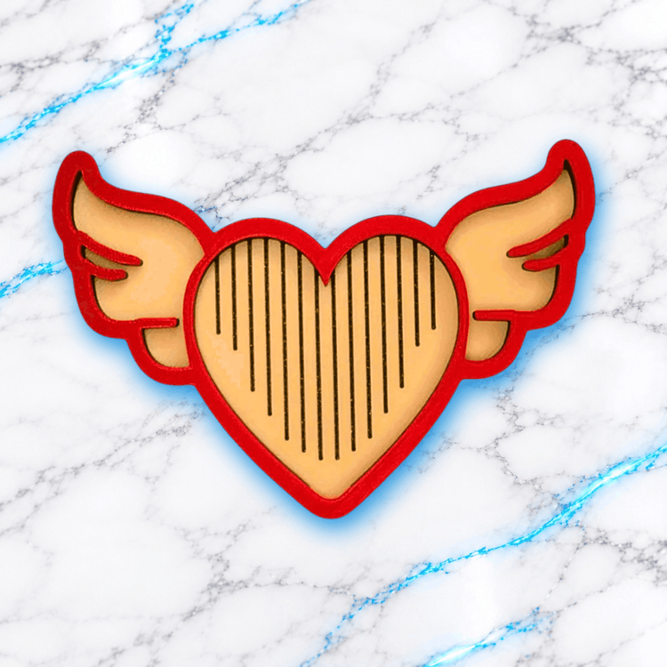 Plateau 3D Diamond Painting Le Love Angel UnBrunBarbu, vue de dessus, en forme de cœur ailé avec contour rouge, intérieur beige et rainures noires pour aligner les diamants, sur fond marbré blanc aux veines bleues.
