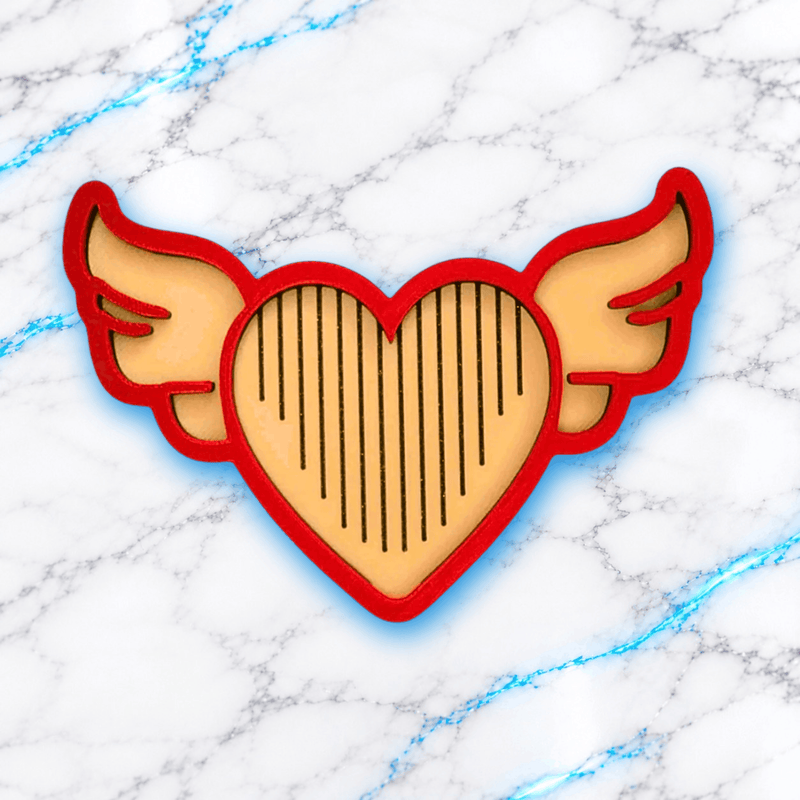 Plateau 3D Diamond Painting Le Love Angel UnBrunBarbu, vue de dessus, en forme de cœur ailé avec contour rouge, intérieur beige et rainures noires pour aligner les diamants, sur fond marbré blanc aux veines bleues.