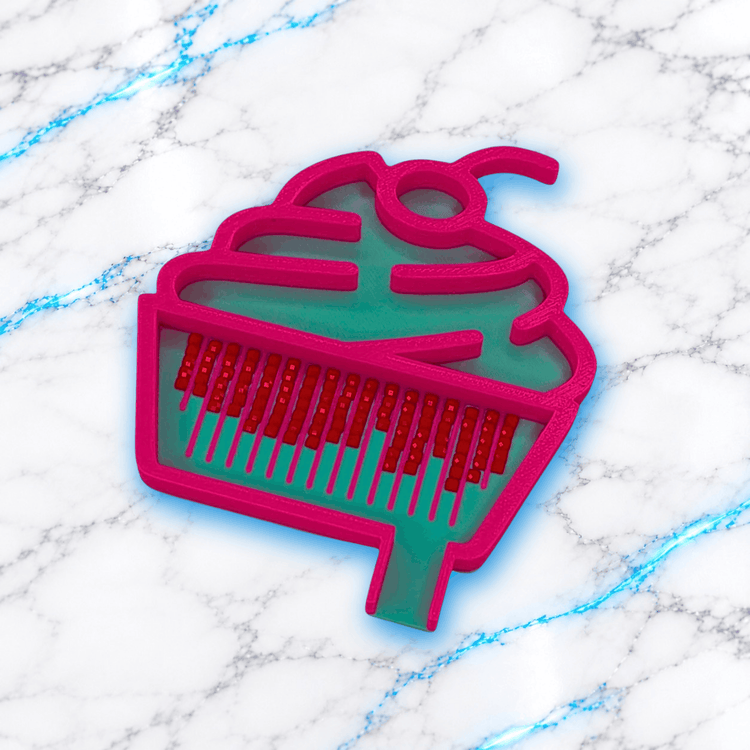 Plateau 3D Diamond Painting Le Petit Cupcake UnBrunBarbu, en forme de cupcake avec contour rose fuchsia, fond turquoise, rainures de tri roses et diamants carrés rouges alignés, sur marbre blanc veiné de bleu.