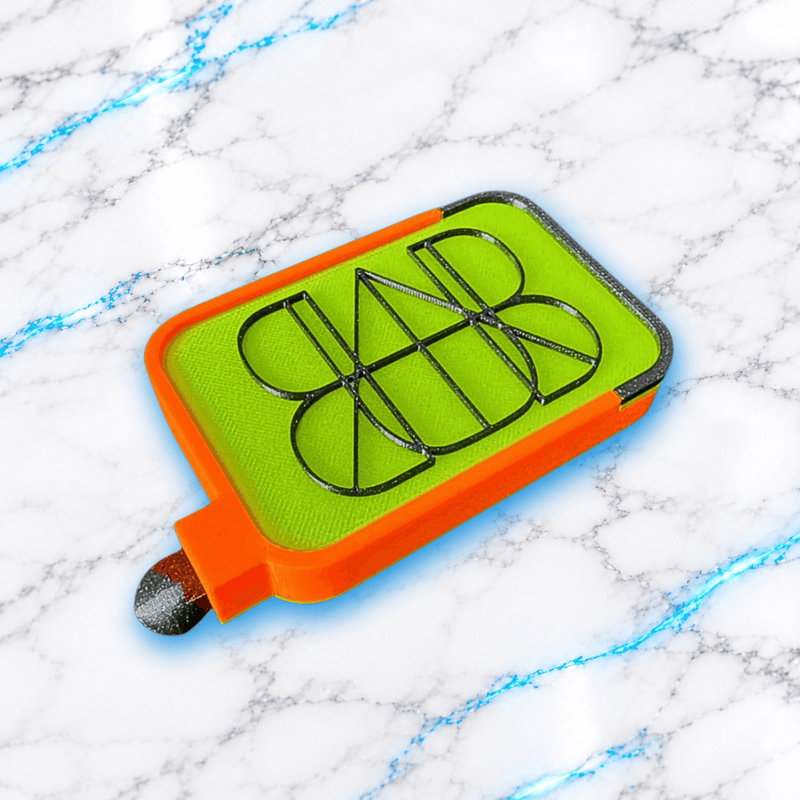 Plateau 3D Diamond Painting Le No Washi Wavy UnBrunBarbu, modèle vert anis et orange avec motifs géométriques noirs en relief, présenté en vue de dessus légèrement inclinée avec son bouchon, sur fond marbré blanc aux veines bleues.