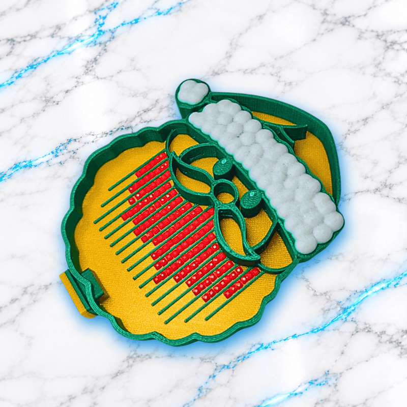 Plateau 3D Diamond Painting Père Noël UnBrunBarbu vu de dessus, en forme de tête de Père Noël avec bonnet vert et blanc, fond doré, rainures vertes et diamants carrés rouges, sur fond marbré blanc et bleu.