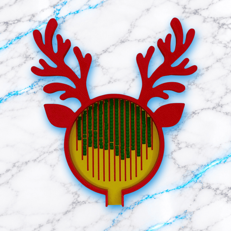 Plateau 3D Diamond Painting Le Renne de Noël UnBrunBarbu, en forme de tête de renne avec bois et oreilles rouges, fond jaune à rainures rouges et diamants verts alignés, sur marbre blanc veiné de bleu.