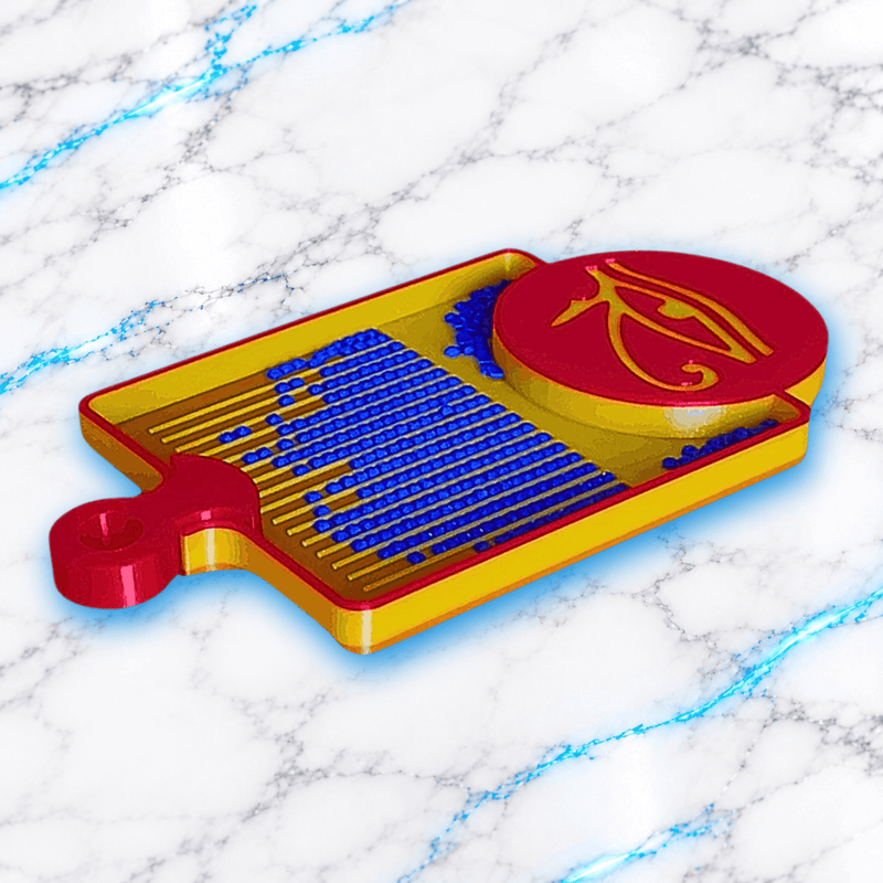 Vue de profil du plateau 3D Diamond Painting Symbole Égyptien UnBrunBarbu, avec bordures dorées et rouges, médaillon rouge orné de l’œil d’Horus doré et rainures remplies de diamants bleus, sur fond marbré blanc et bleu.