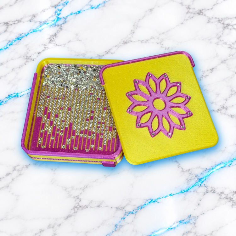 Plateau Diamond Painting Flower Strass jaune et rose ouvert, contenant des diamants argentés, avec couvercle à fleur ornée de strass posé à droite.