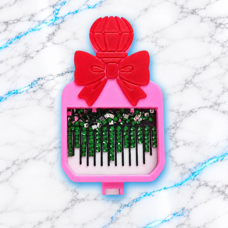 Vue du dessus du plateau Diamond Painting Parfum rose avec nœud rouge et diamants carrés verts alignés dans les rainures noires.